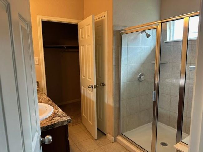 Full bathroom featuring vanity, a shower stall, tile patterned floors, and a walk in closet | Image 4