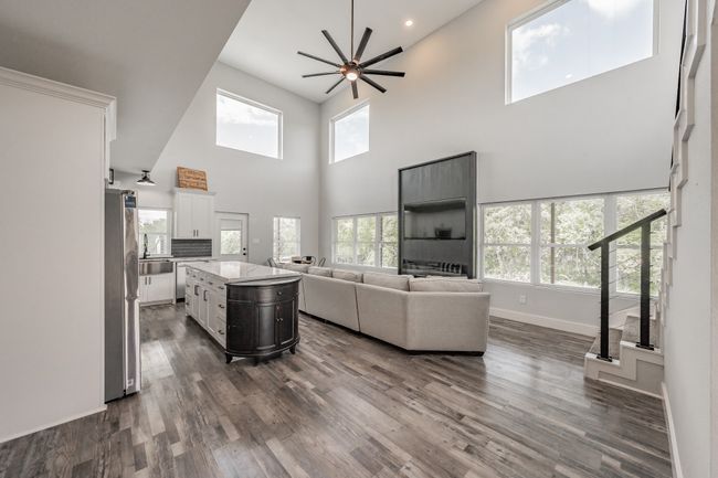 Living room with a towering ceiling, a ceiling fan, dark wood-style flooring, baseboards, and recessed lighting | Image 18