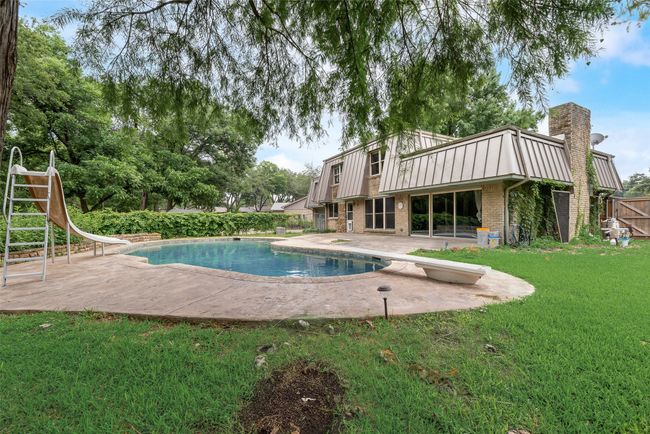 View of swimming pool with a water slide, a patio area, and a diving board | Image 34
