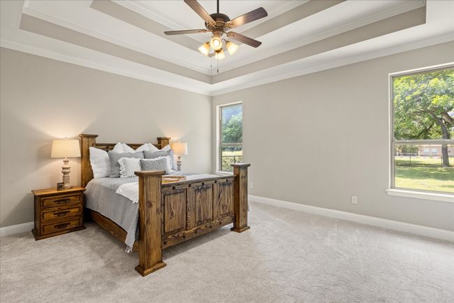 Bedroom with a raised ceiling, crown molding, light colored carpet, and ceiling fan | Image 21