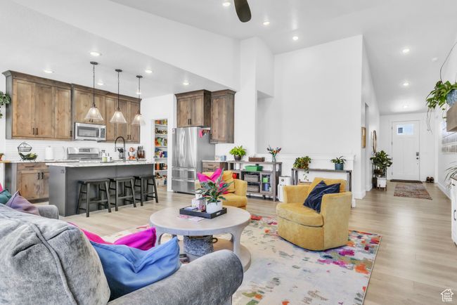 Living room with light wood-style flooring, recessed lighting, ceiling fan, and high vaulted ceiling | Image 9