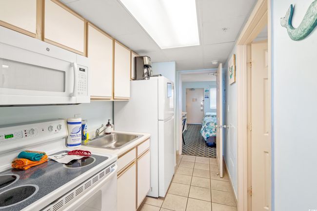 Kitchen with white appliances, light tile patterned flooring, and light countertops | Image 12