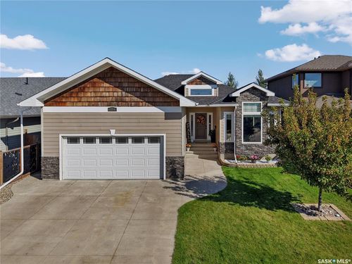 Exterior featuring stone accents, horizontal siding, wood-finish shingles, a multi-pane garage door, and a concrete driveway | Card Image