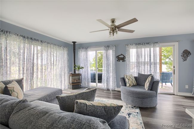 Living room with plenty of natural light, ceiling fan, dark hardwood / wood-style flooring, and a wood stove | Image 29