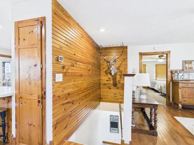 Hall featuring wood walls and hardwood floors with stairs leading to lower level | Image 46
