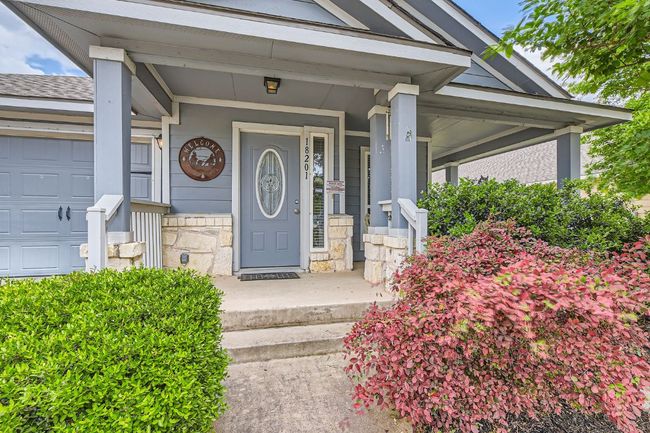 View of exterior entry with a garage, stone siding, and covered porch | Image 4