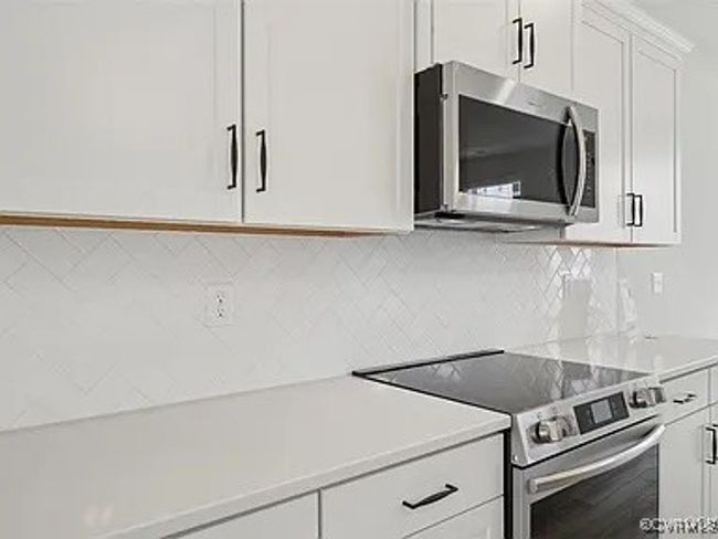 Kitchen featuring appliances with stainless steel finishes, light countertops, white cabinets, and decorative backsplash | Image 9
