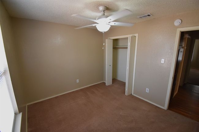 Unfurnished bedroom with carpet flooring, a textured ceiling, a closet, and ceiling fan | Image 11