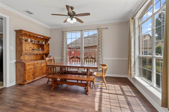 Dining room featuring dark wood-style flooring, a ceiling fan, and crown molding | Image 8