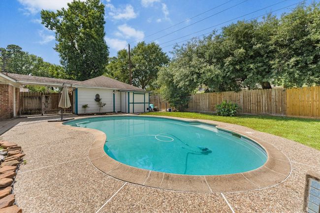View of pool with a fenced backyard and an outdoor structure | Image 5
