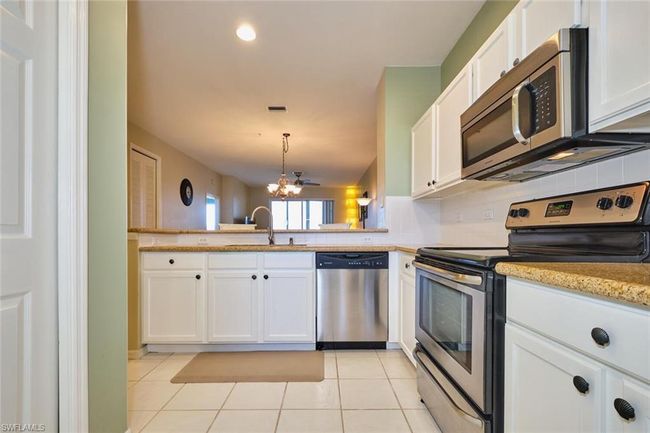 Kitchen featuring appliances with stainless steel finishes, a notable chandelier, light tile patterned flooring, decorative backsplash, and a sink | Image 19