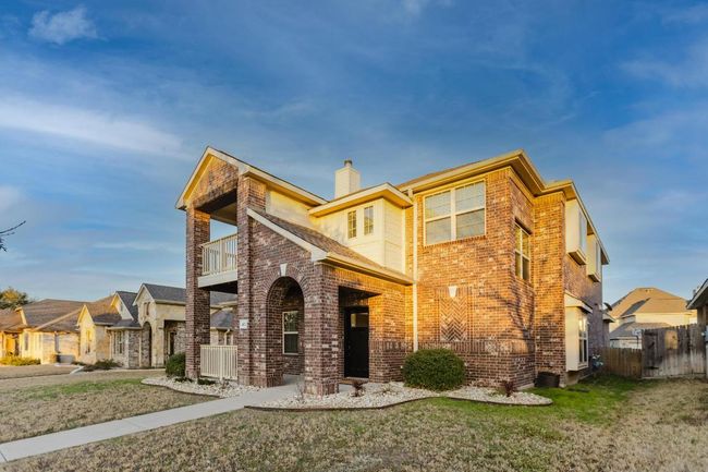 View of front of property featuring brick siding, a chimney, a balcony, and fence | Image 37