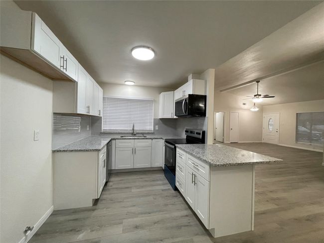 Kitchen with white cabinetry, stainless steel appliances, light stone countertops, and sink | Image 7