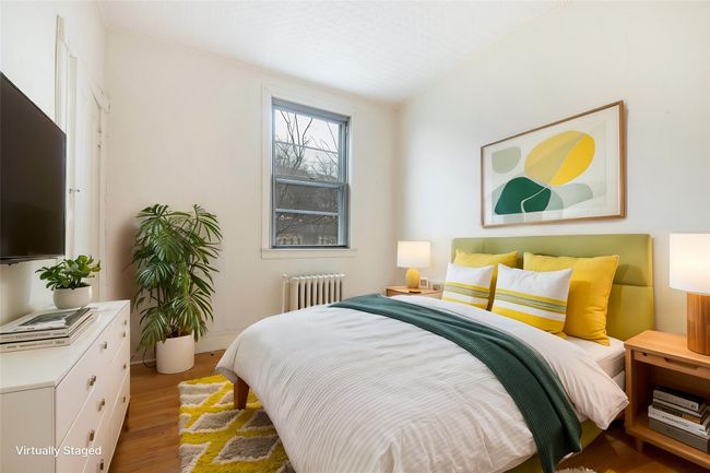 Bedroom featuring baseboards, radiator heating unit, and wood finished floors | Image 15