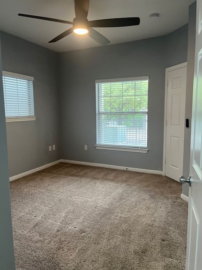 Carpeted empty room featuring a healthy amount of sunlight, a ceiling fan, and baseboards | Image 15