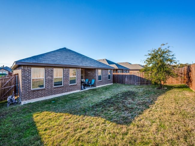 Rear view of property featuring brick siding, a fenced backyard, and a shingled roof | Image 25