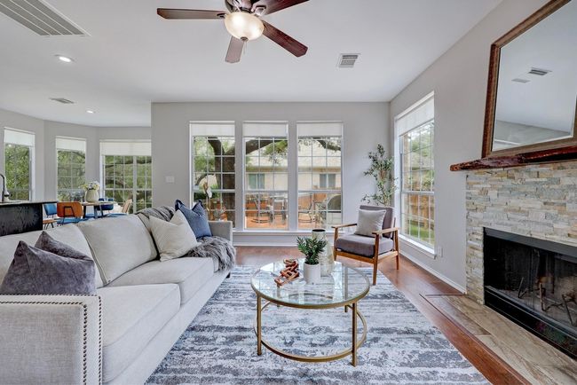 Living area with ceiling fan, wood finished floors, a fireplace, recessed lighting, and baseboards | Image 11