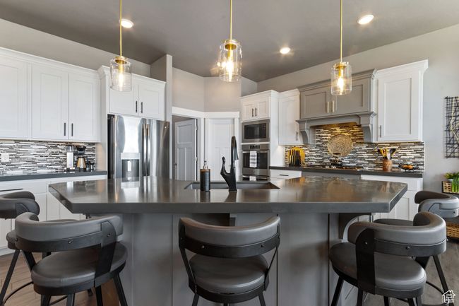 Kitchen featuring dark countertops, appliances with stainless steel finishes, decorative backsplash, and a sink | Image 5