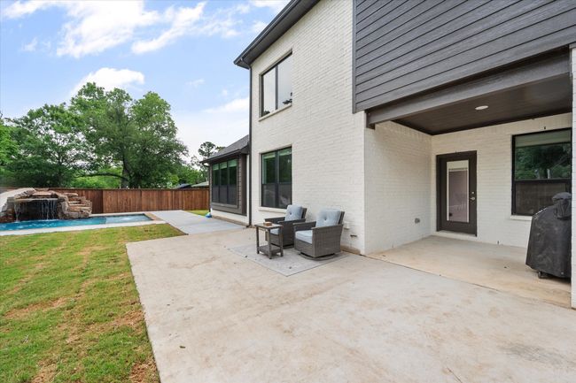 Backyard retreat includes covered patio space and in-ground pool. | Image 35