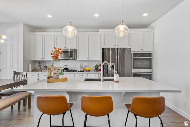 Kitchen with white cabinets, appliances with stainless steel finishes, decorative backsplash, and a sink | Image 25