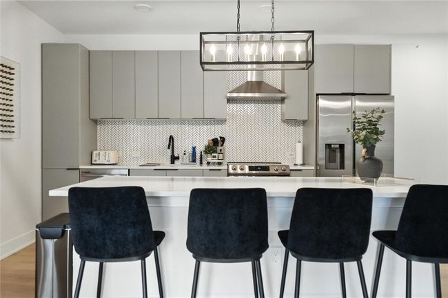Kitchen featuring appliances with stainless steel finishes, gray cabinetry, light countertops, and decorative backsplash | Image 6