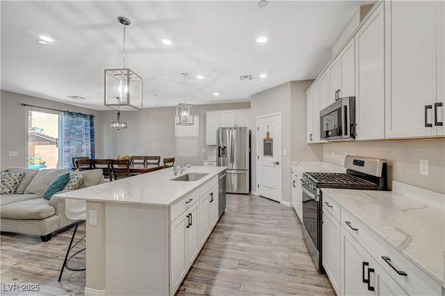 Kitchen with appliances with stainless steel finishes, a breakfast bar area, light wood-type flooring, open floor plan, and recessed lighting | Image 21