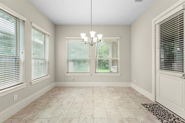 This bright breakfast nook is the perfect spot for your morning coffee—wall-to-wall windows flood the space with light and give you a peek at the backyard. The tiled floor makes cleanup a breeze, and the handy door right there means you can step straight outside for an afternoon BBQ or evening hangout. | Image 9