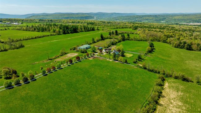 Aerial view of sparsely populated area featuring mountains and agricultural land | Image 9