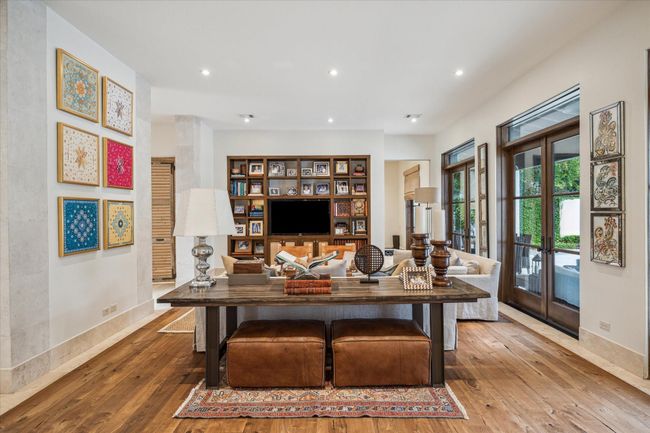 The great room with high ceilings, walnut flooring and a wall of French doors overlooking the outdoor entertaining area and pool. | Image 12