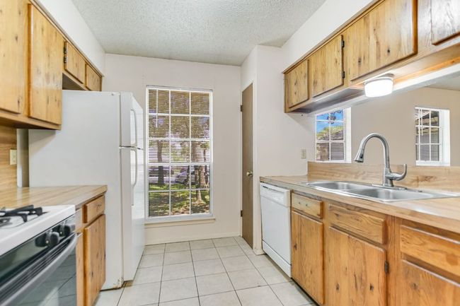 Kitchen with a sink, dishwasher, light countertops, a textured ceiling, and plenty of natural light | Image 10