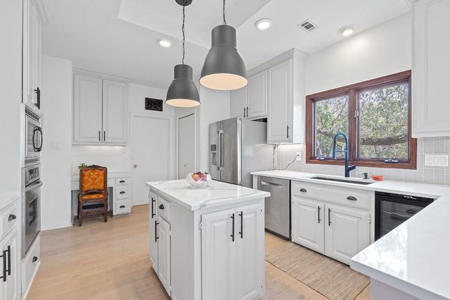 Kitchen with stainless steel appliances, decorative backsplash, white cabinets, and recessed lighting | Image 11