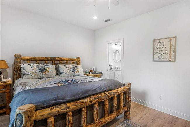Bedroom featuring ensuite bath, light wood-style flooring, baseboards, visible vents, and a ceiling fan | Image 17