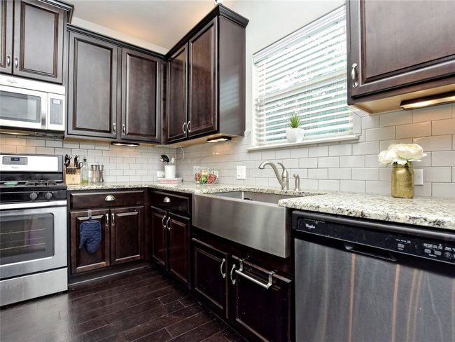 Kitchen with granite counters, stainless appliances, espresso cabinetry, and center island. | Image 9