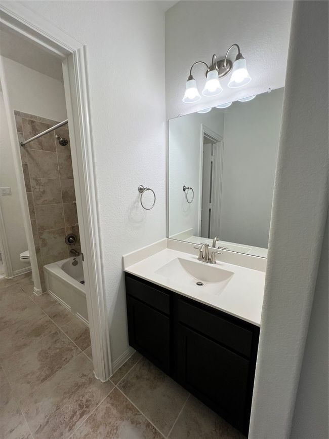 Bathroom with vanity, washtub / shower combination, and light tile patterned floors | Image 25