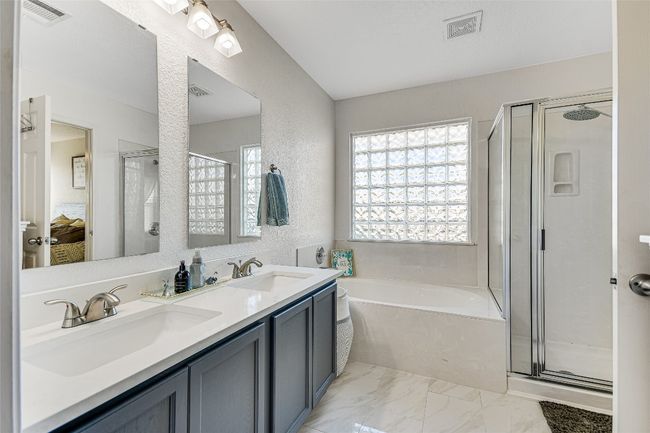 Bathroom with ensuite bath, a bath, a shower stall, double vanity, and a textured wall | Image 14
