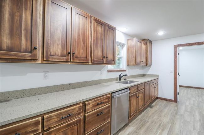 Kitchen with dishwasher, light stone countertops, sink, and light hardwood / wood-style floors | Image 18
