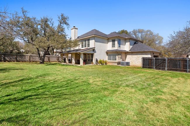 Rear view of house featuring a fenced backyard, a chimney, a yard, and a shingled roof | Image 38