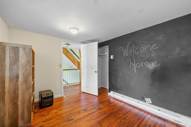 Unfurnished bedroom with a baseboard radiator, hardwood / wood-style floors, a closet, and baseboards | Image 10