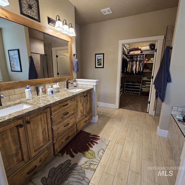 Full bathroom featuring wood finished floors, double vanity, a walk in closet, and a shower with shower curtain | Image 17
