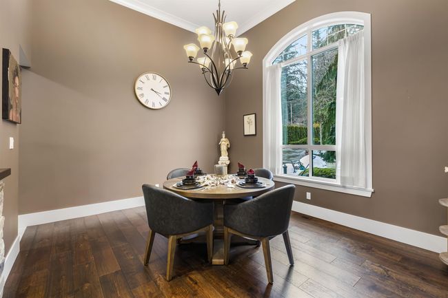 Dining space with ornamental molding, dark wood-style flooring, a notable chandelier, and baseboards | Image 9