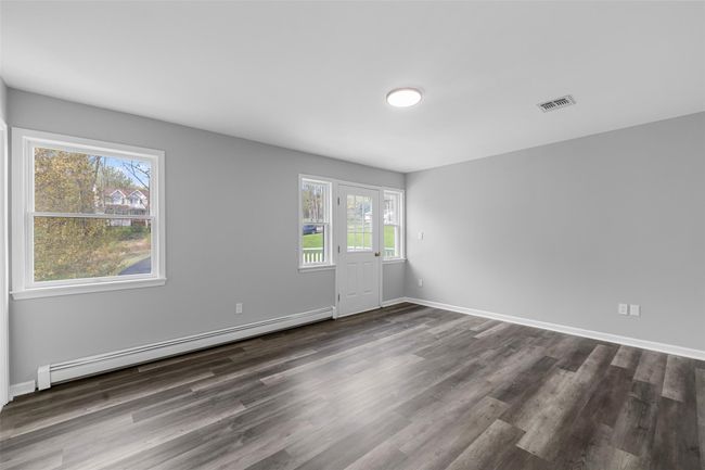 Spare room featuring dark wood finished floors, visible vents, baseboards, and a baseboard radiator | Image 19