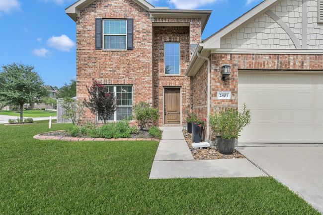 With intricate brick work, wood shake siding, and its charming rustic wooden entry door, this home makes a striking first impression. | Image 4