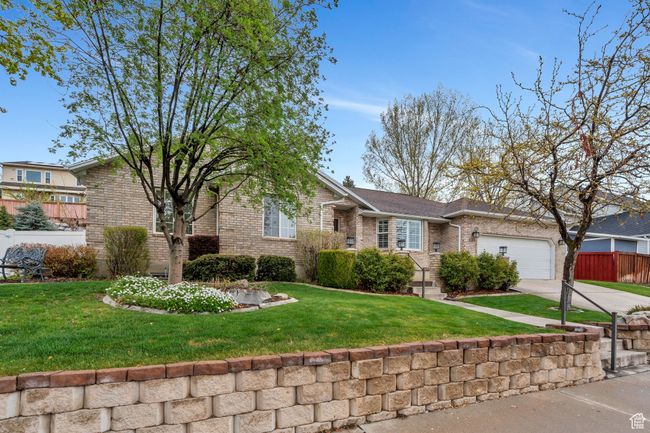 Ranch-style home featuring concrete driveway, an attached garage, fence, a front yard, and brick siding | Image 44