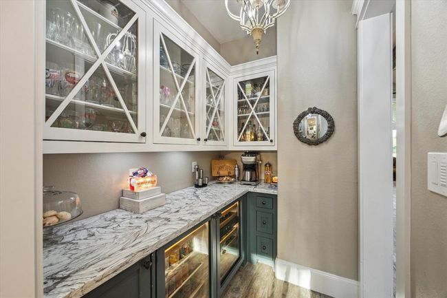The butler’s pantry is further enhanced with elegant quartz countertops, providing a sleek and durable surface. With a beverage refrigerator, wine refrigerators for both white and red wine, a Scotts ice maker, and custom glass-door cabinets, this space combines style and functionality seamlessly. | Image 11