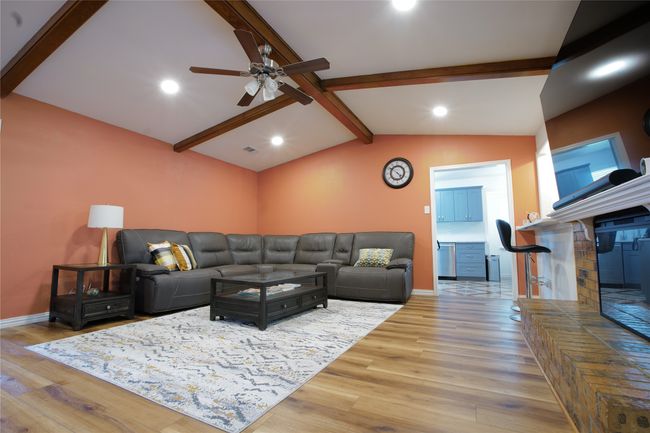 Living area featuring wood finished floors, ceiling fan, a brick fireplace, and recessed lighting | Image 8