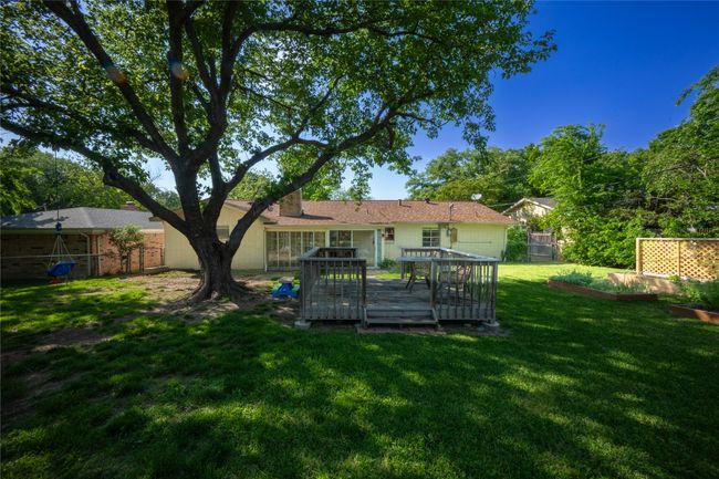 Rear view of house with a deck, a lawn, a garden, and fence | Image 22