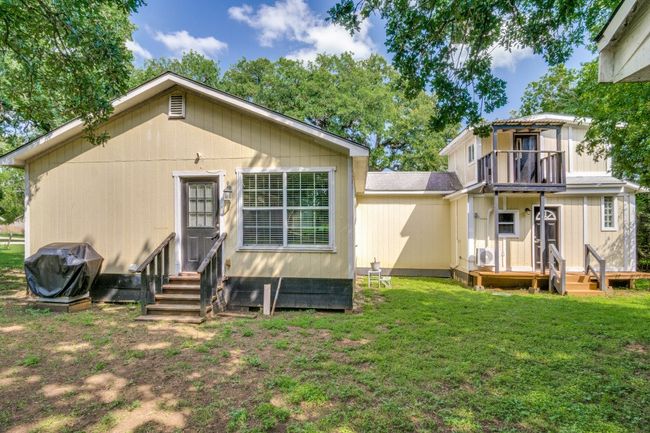 Back of house with a balcony, entry steps, and a lawn | Image 23