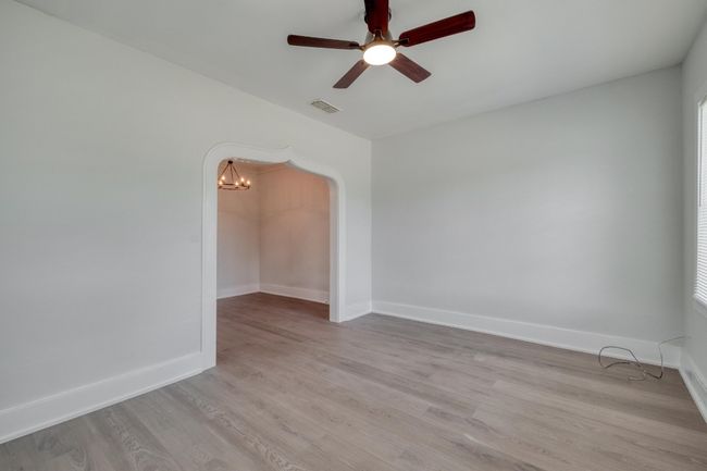 Unfurnished room featuring ceiling fan, light wood-style flooring, a chandelier, and arched walkways | Image 8