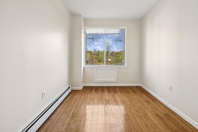 Empty room featuring a baseboard radiator, baseboards, and light wood-style floors | Image 6