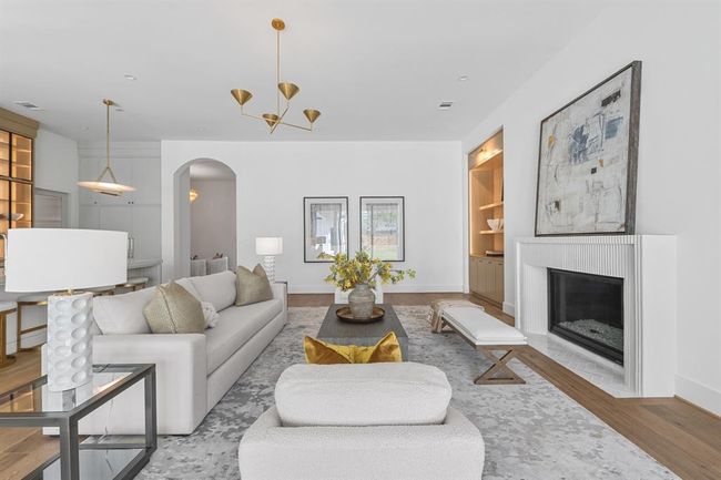 At the heart of the home, the main living space is a masterclass in refined comfort—where natural light pours in through expansive glass doors and highlights the bespoke plaster fireplace, white oak accents, and elevated finishes throughout. | Image 21